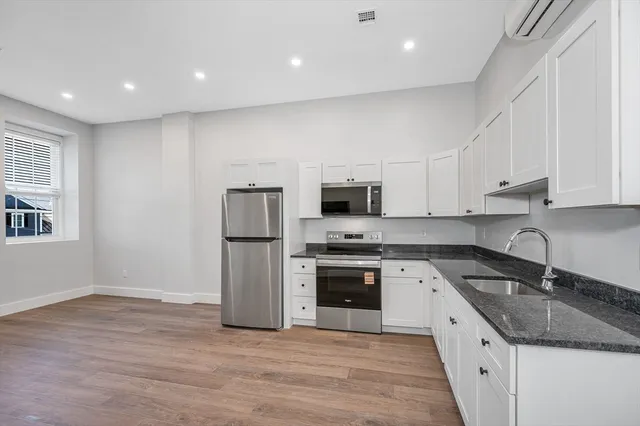 a kitchen with stainless steel appliances granite countertop a sink a stove a refrigerator and white cabinets