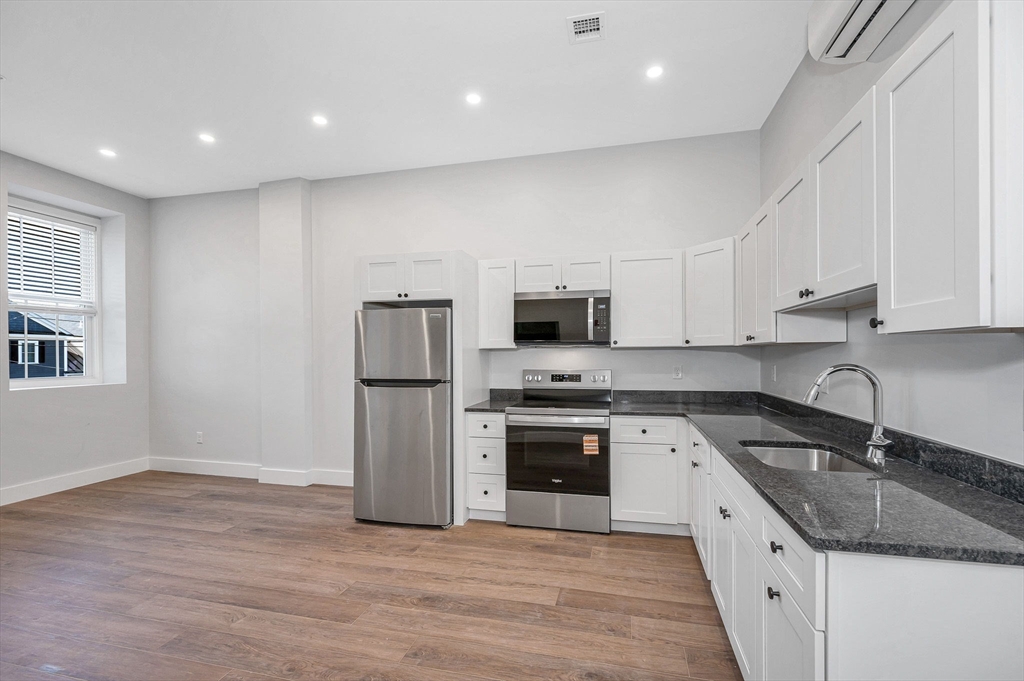241 West 6th Street, Unit 102 Lowell, MA 01850 - Photo 13 of 25 a kitchen with stainless steel appliances granite countertop a sink a stove a refrigerator and white cabinets