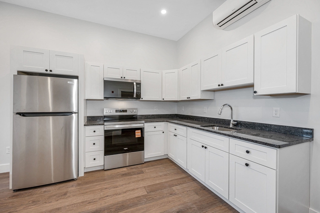 241 West 6th Street, Unit 102 Lowell, MA 01850 - Photo 14 of 25 a kitchen with granite countertop a refrigerator sink and cabinets
