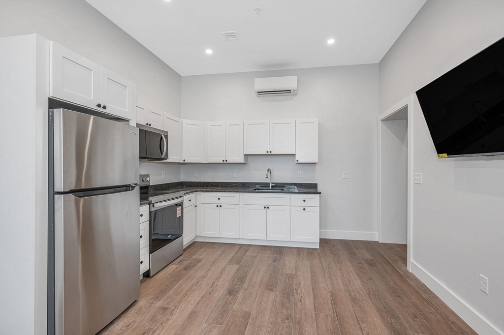 241 West 6th Street, Unit 102 Lowell, MA 01850 - Photo 3 of 25 a kitchen with a refrigerator a microwave and sink