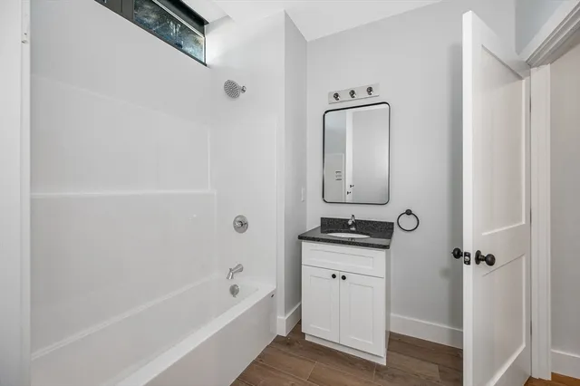 a bathroom with a granite countertop sink a mirror and bathtub