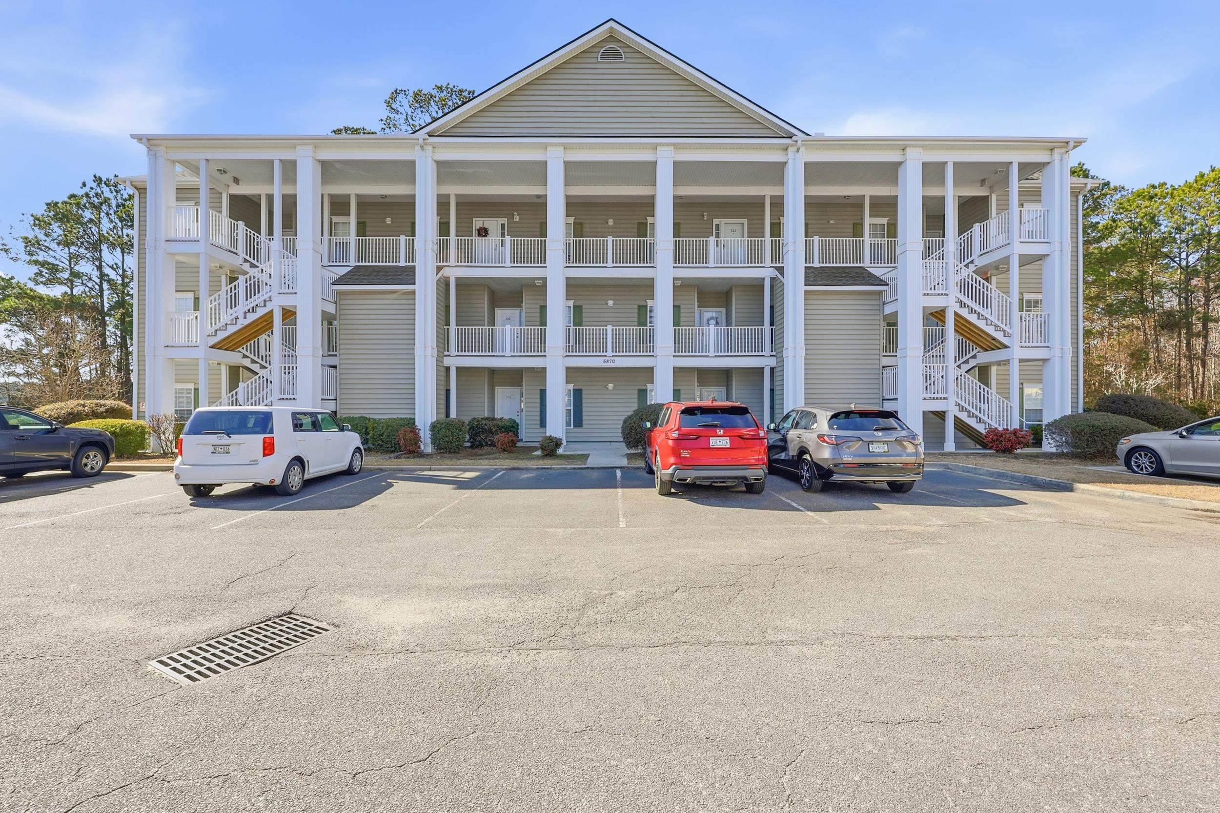 View of apartment building / complex featuring stairway and uncovered parking