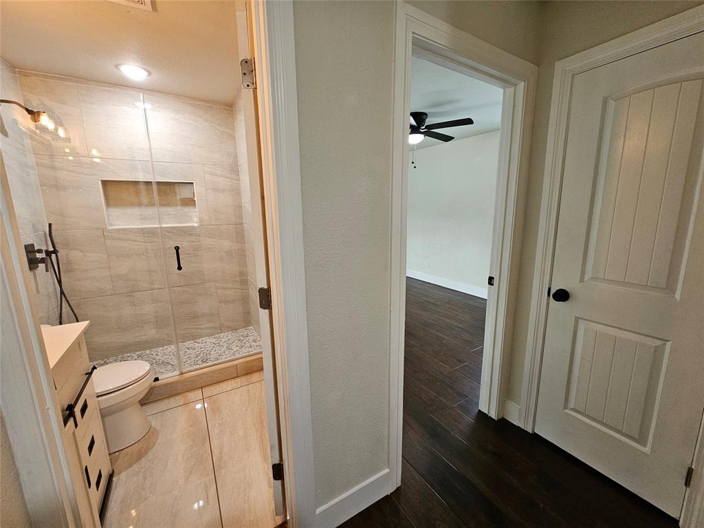 211 North Hampton Road Dallas, TX 75208 - Photo 16 of 22 Bathroom featuring a glass-enclosed shower with a tiled niche, a toilet, and light-toned floor tiling