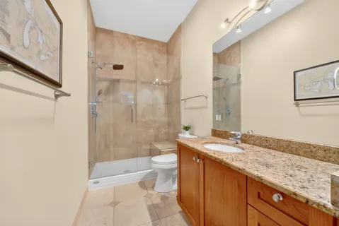 a bathroom with a granite countertop sink a toilet a mirror and shower