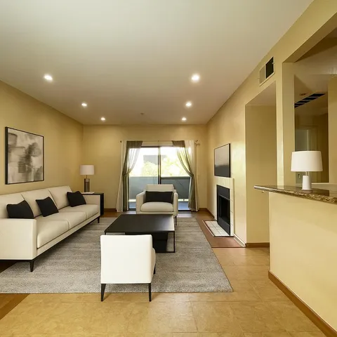 a living room with couches and kitchen view with wooden floor