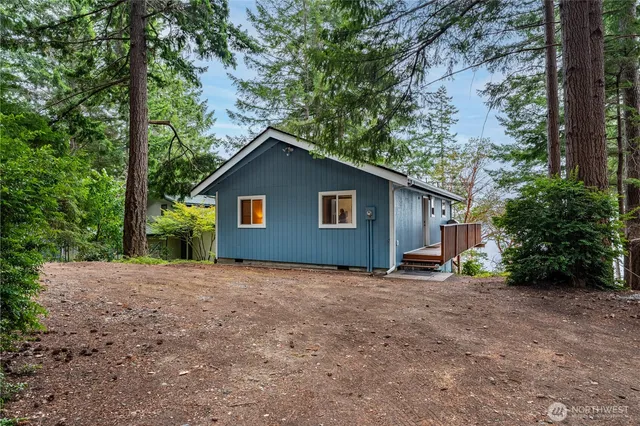 a view of a house with large tree and wooden fence