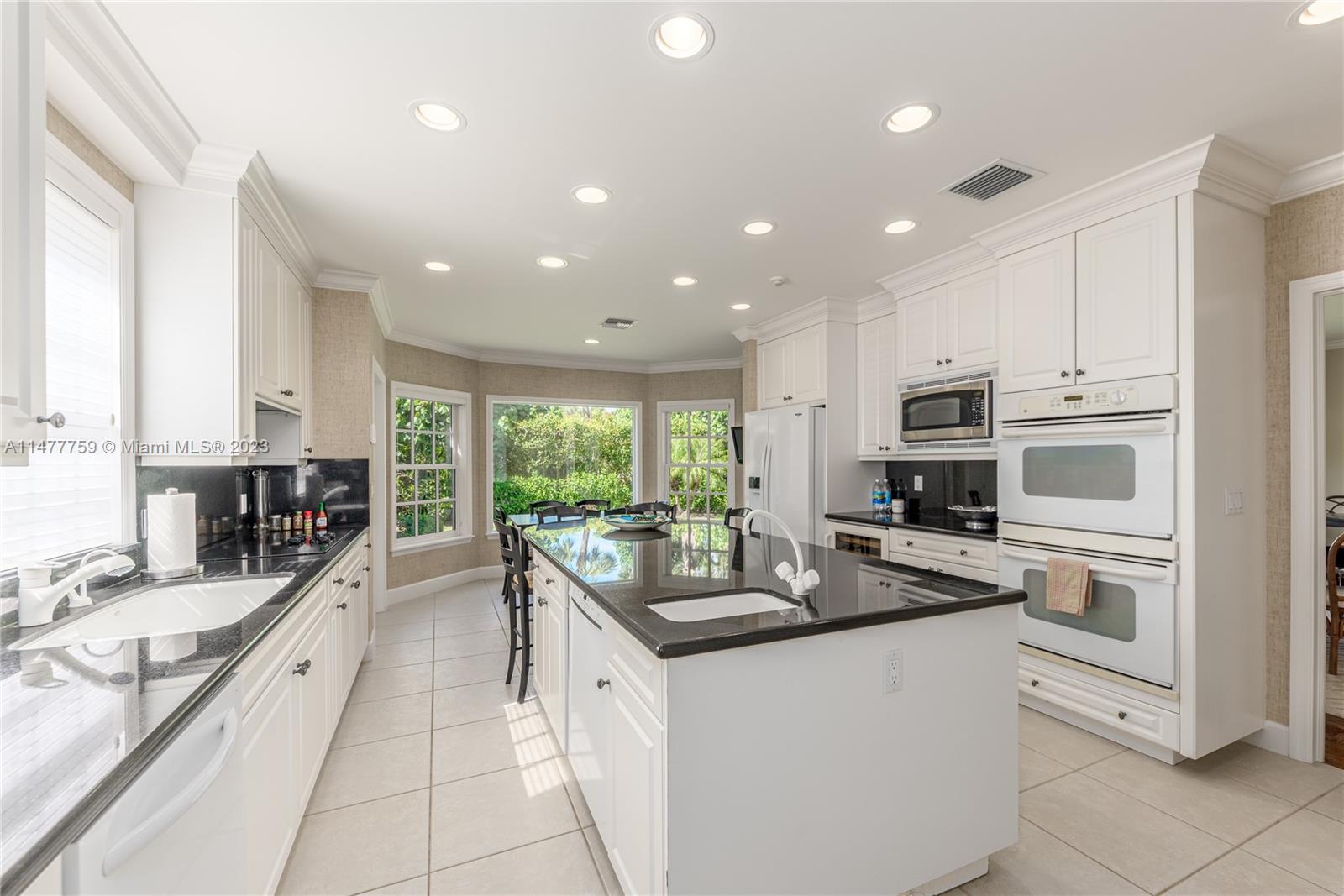 111 Gomez Road Hobe Sound, FL 33455 - Photo 7 of 16 a kitchen with stainless steel appliances kitchen island granite countertop a sink and cabinets