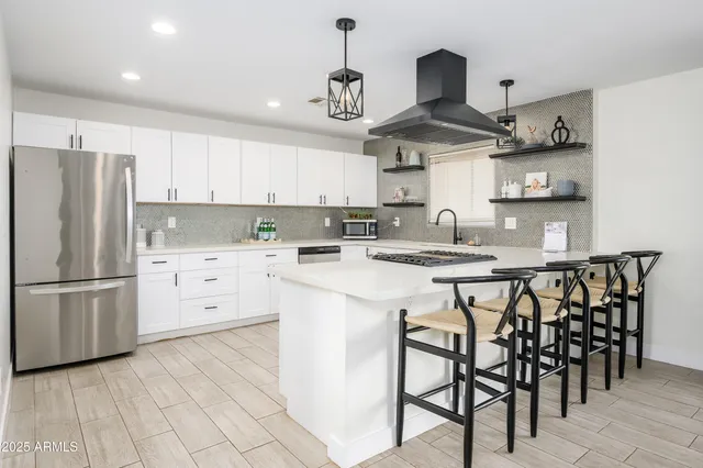 a kitchen with kitchen island granite countertop stainless steel appliances a stove a sink and cabinets