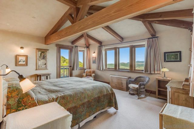 a bedroom with a bed and large windows