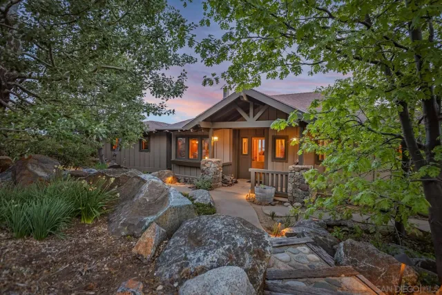 a front view of a house with a yard and mountain view in back