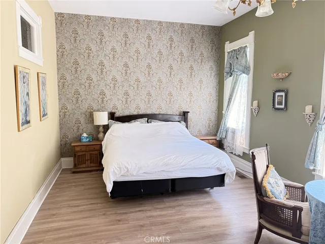 a bed sitting in a bedroom next to a window with wooden floor