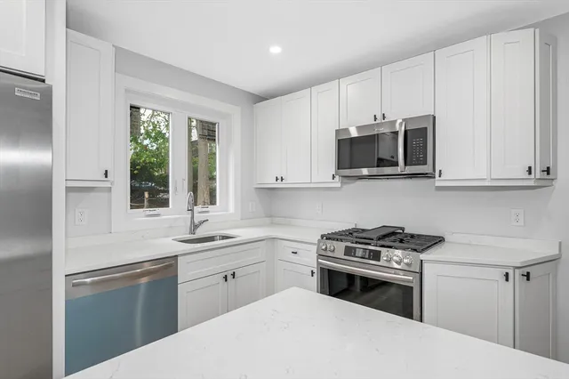 a kitchen with cabinets appliances a sink and a window