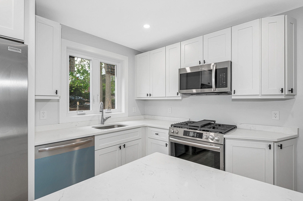 1514 Gorham Street, Unit 4 Lowell, MA 01852 - Photo 12 of 42 a kitchen with cabinets appliances a sink and a window