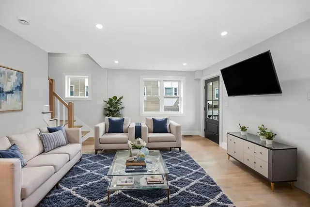 a living room with furniture a flat screen tv and a window