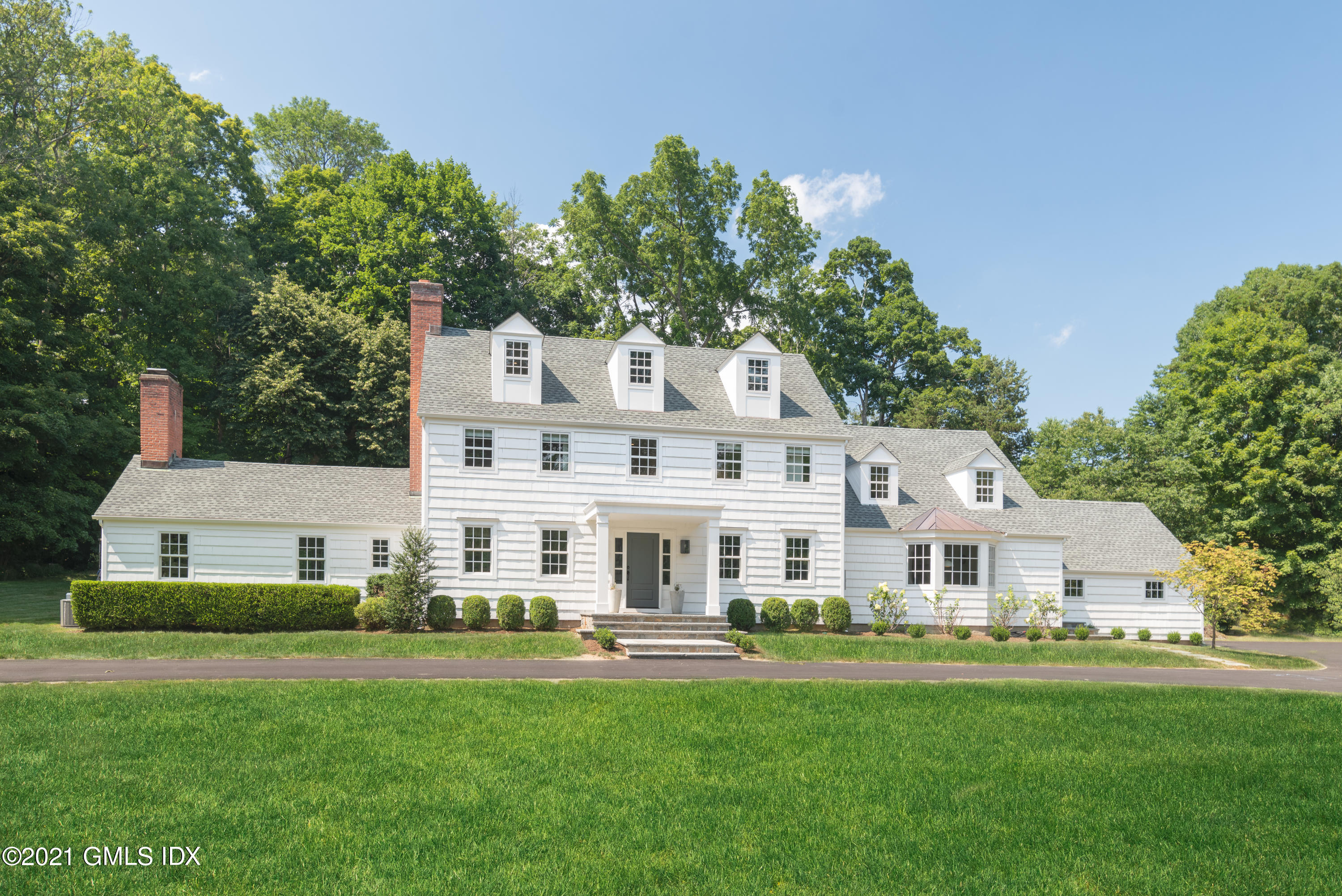 a front view of a house with a garden and trees