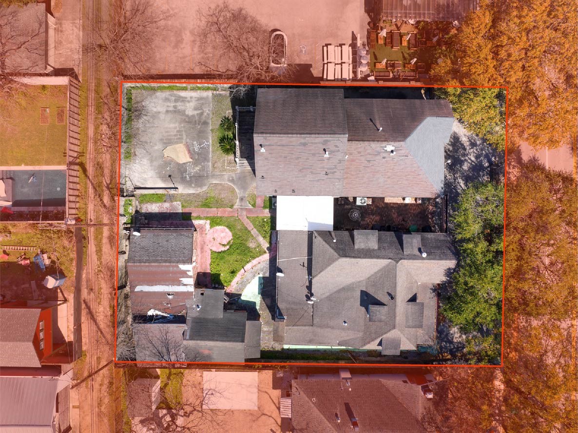 an aerial view of a house with a yard and a large tree