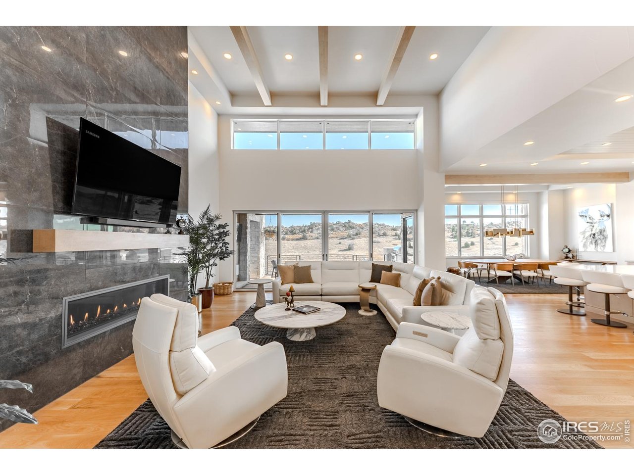 7572 Raphael Lane Littleton, CO 80125 - Photo 13 of 50 Rising to twenty feet, the great room embodies the grandeur of contemporary living, where minimalist lines and light converge in sophisticated harmony. A white-oak beamed ceiling crowns the space while clerestory windows illuminate with natural light.