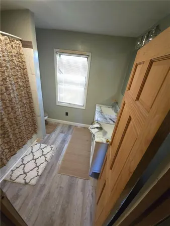 a view of an empty room with window and wooden floor