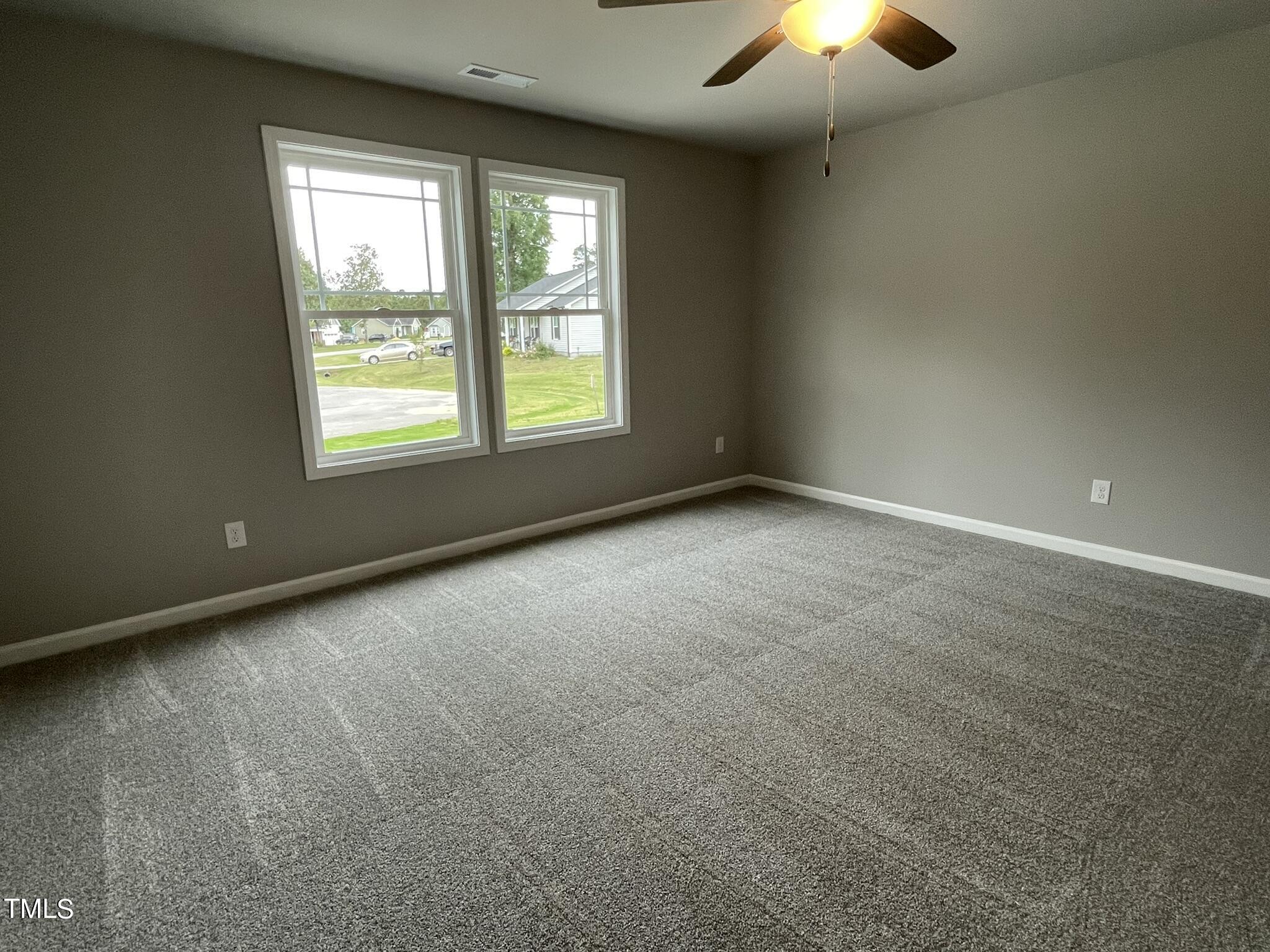 329 Ewing Drive Selma, NC 27576 - Photo 11 of 17 an empty room with a chandelier fan and windows