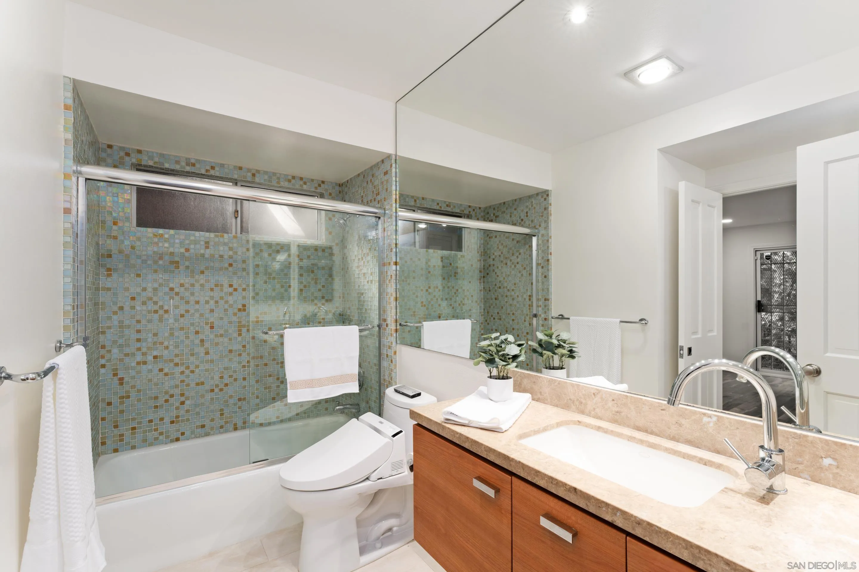 5665 Soledad Mountain Road La Jolla, CA 92037 - Photo 31 of 52 a bathroom with a granite countertop sink a toilet a mirror and shower