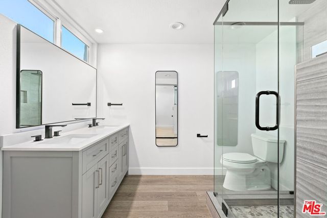 a bathroom with a double vanity sink toilet and shower