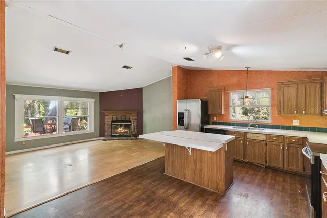 a large kitchen with kitchen island granite countertop a stove a sink and dishwasher wooden cabinets with wooden floor