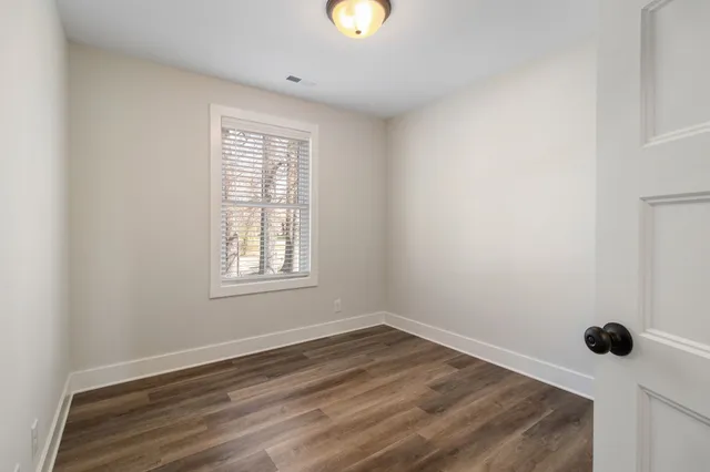 a view of an empty room with wooden floor and window
