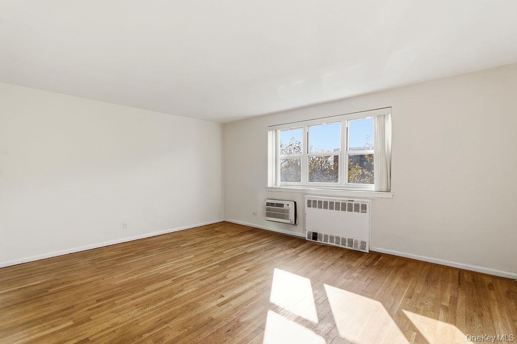 153-25 88th Street, Unit 4N Queens, NY 11414 - Photo 2 of 11 an empty room with wooden floor and windows