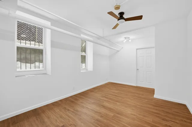 a view of empty room with wooden floor and fan