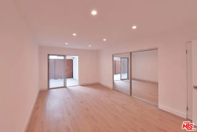 an empty room with wooden floor and natural light
