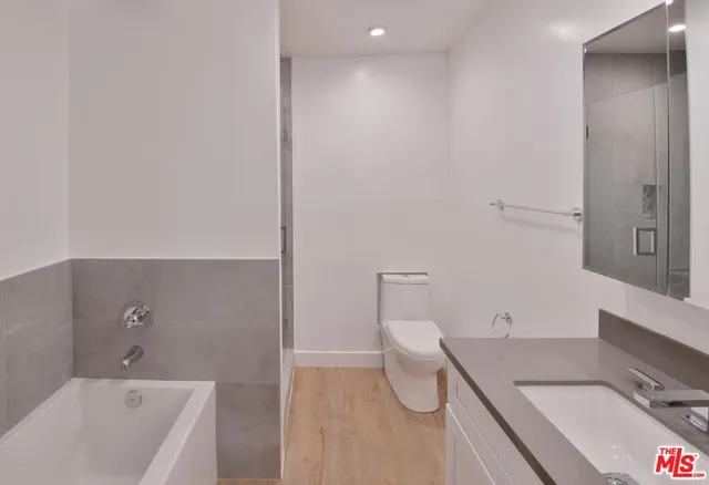 a bathroom with a granite countertop sink a toilet and bathtub