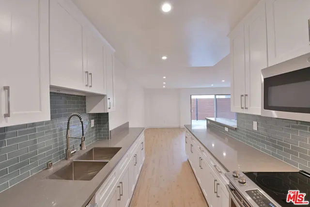 a large kitchen with stainless steel appliances granite countertop a sink a stove and a microwave