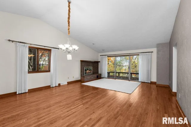a view of empty room with wooden floor and fireplace