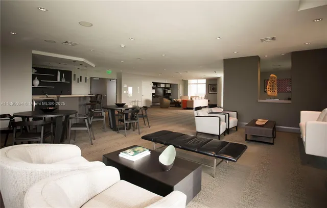 a living room with furniture a wooden floor and kitchen view