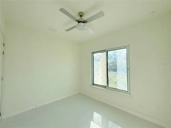 an empty room with ceiling fan and windows