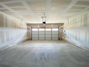 213 Saide Street Georgetown, TX 78626 - Photo 16 of 32 Spacious garage with a sectional garage door, exposed ceiling joists, and concrete flooring