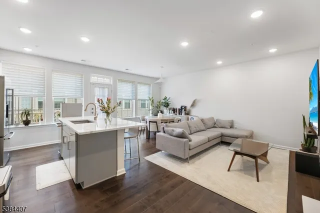 a kitchen with stainless steel appliances a sink a stove a refrigerator cabinets and a dining table