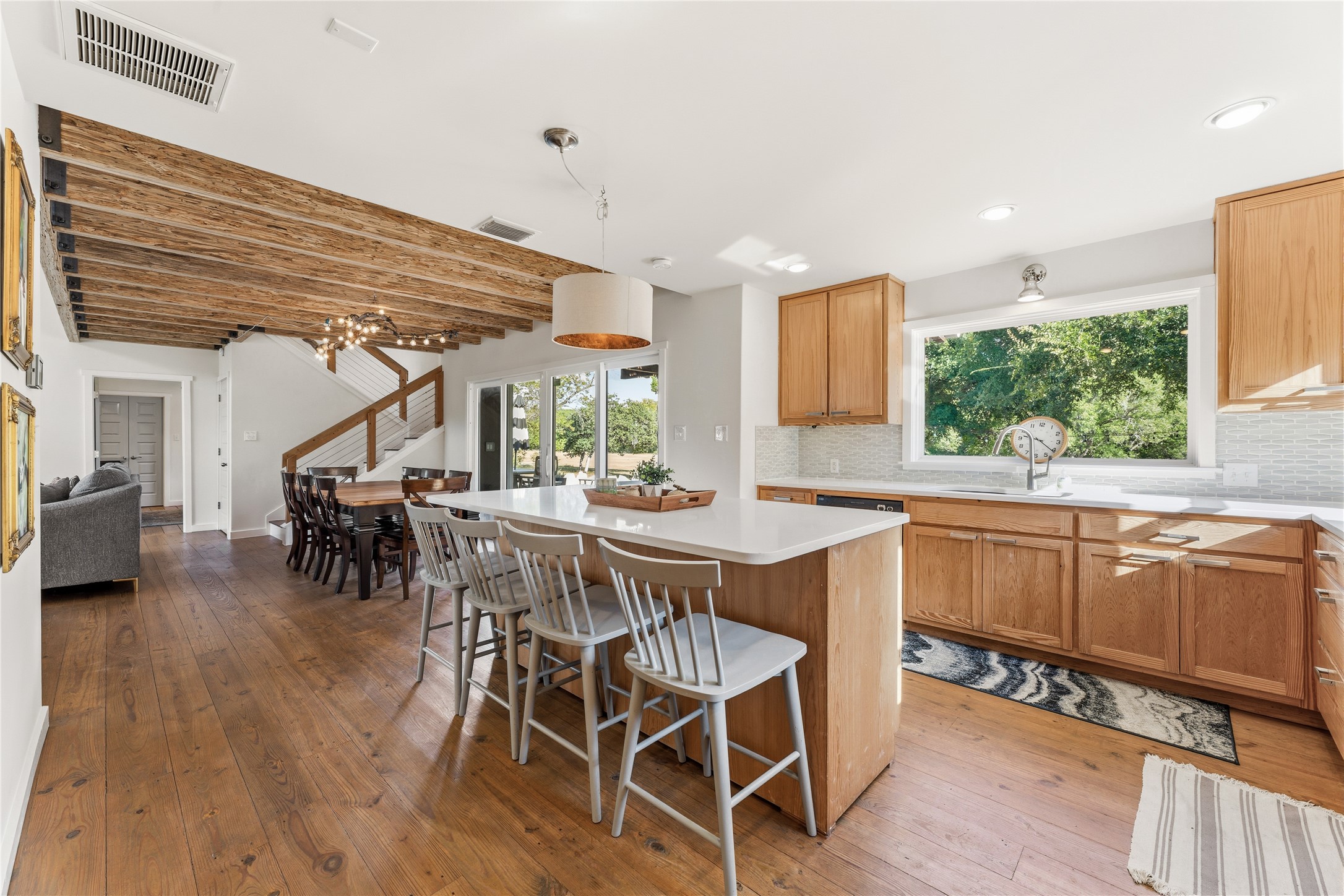 12901 Wire Road Leander, TX 78641 - Photo 5 of 40 Exposed ceiling beams and rich wood floors frame this welcoming kitchen and dining space.