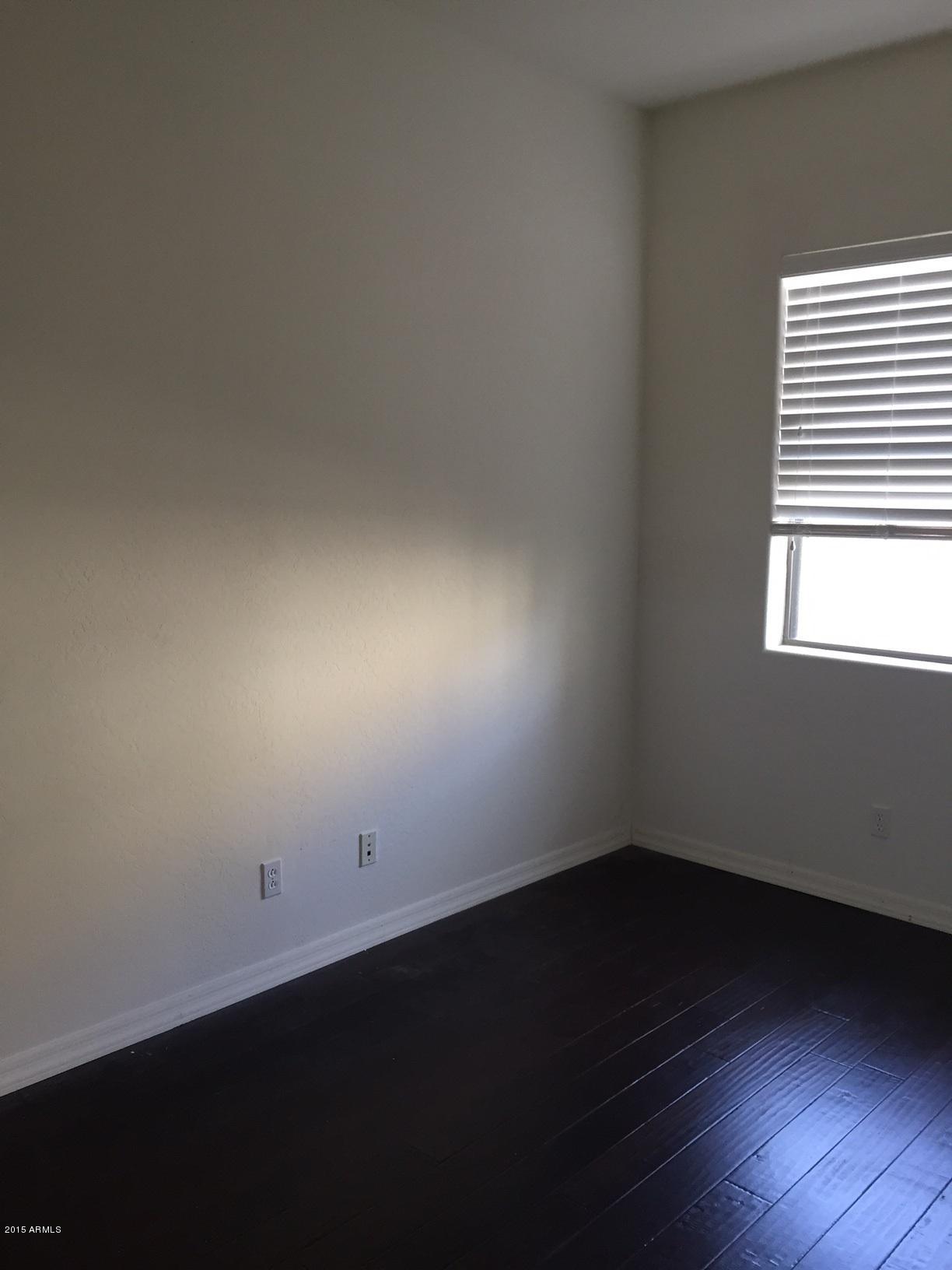 1502 East Dunlap Avenue, Unit 12 Phoenix, AZ 85020 - Photo 13 of 16 an empty room with wooden floor and windows