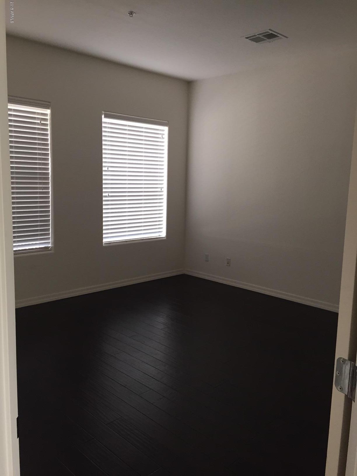 1502 East Dunlap Avenue, Unit 12 Phoenix, AZ 85020 - Photo 8 of 16 a view of an empty room with wooden floor and a window