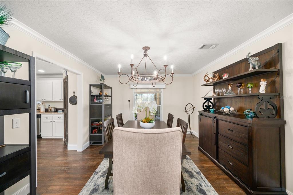 15405 Old Parker Island Road Lake Placid, FL 33852 - Photo 11 of 39 a kitchen with stainless steel appliances kitchen island granite countertop a refrigerator a stove top oven a dining table and chairs with wooden floor