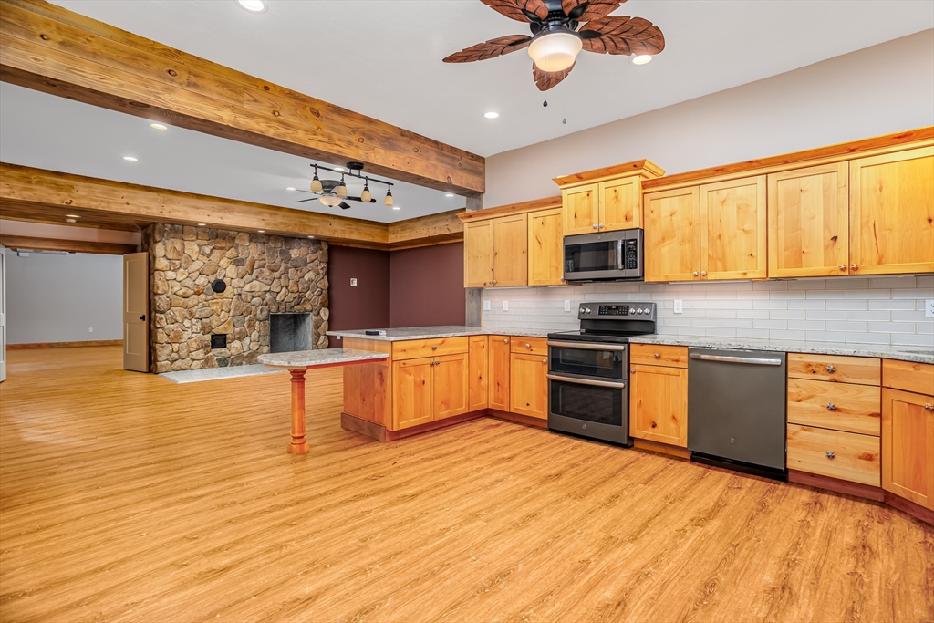 210 Indian Hill Road Groton, MA 01450 - Photo 27 of 42 a kitchen with stainless steel appliances kitchen island granite countertop a stove a sink and a microwave