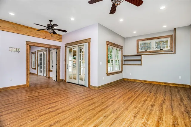 a view of an empty room with window and wooden floor