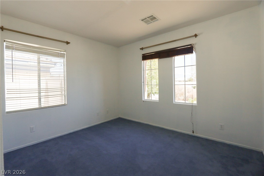 6472 Centennial Road Pahrump, NV 89048 - Photo 12 of 29 A quiet bedroom featuring plush blue carpeting and multiple windows.