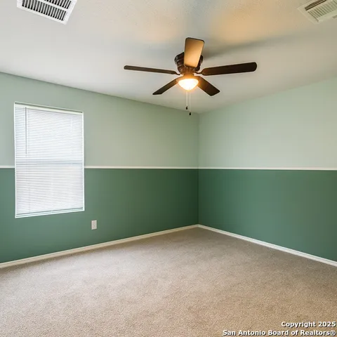an empty room with a window and ceiling fan