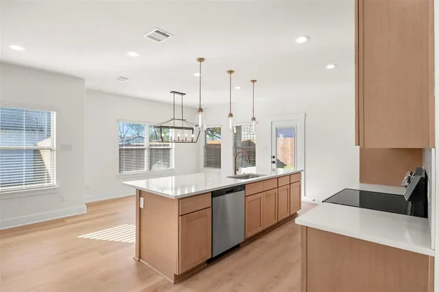 a view of a kitchen with a sink and dishwasher a refrigerator with wooden floor