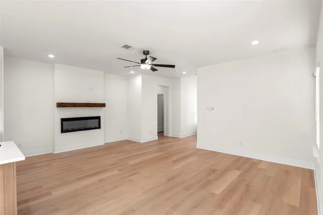 a view of empty room with wooden floor and kitchen