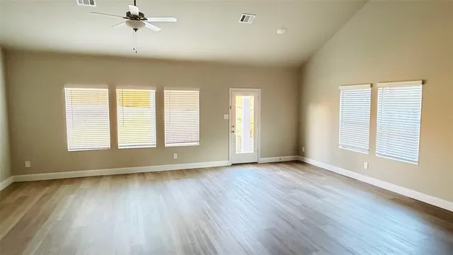 an empty room with wooden floor and windows