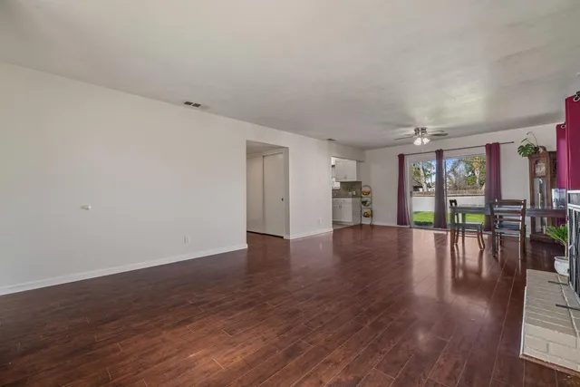a view of an empty room with wooden floor and a fireplace