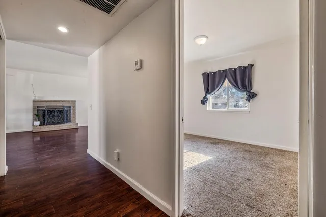 a view of a hallway to room with wooden floor